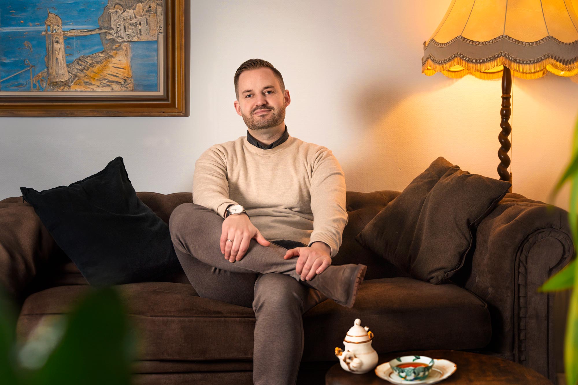 Kristof Sneider auf einer Couch. Vor ihm eine Tasse Ostfriesentee