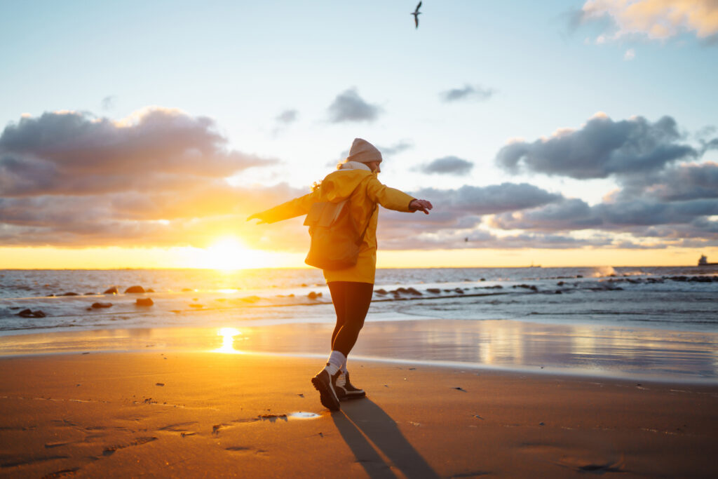 Eine Frau am Meer mit einer Typischen gelben Ostfrieslandjacke an